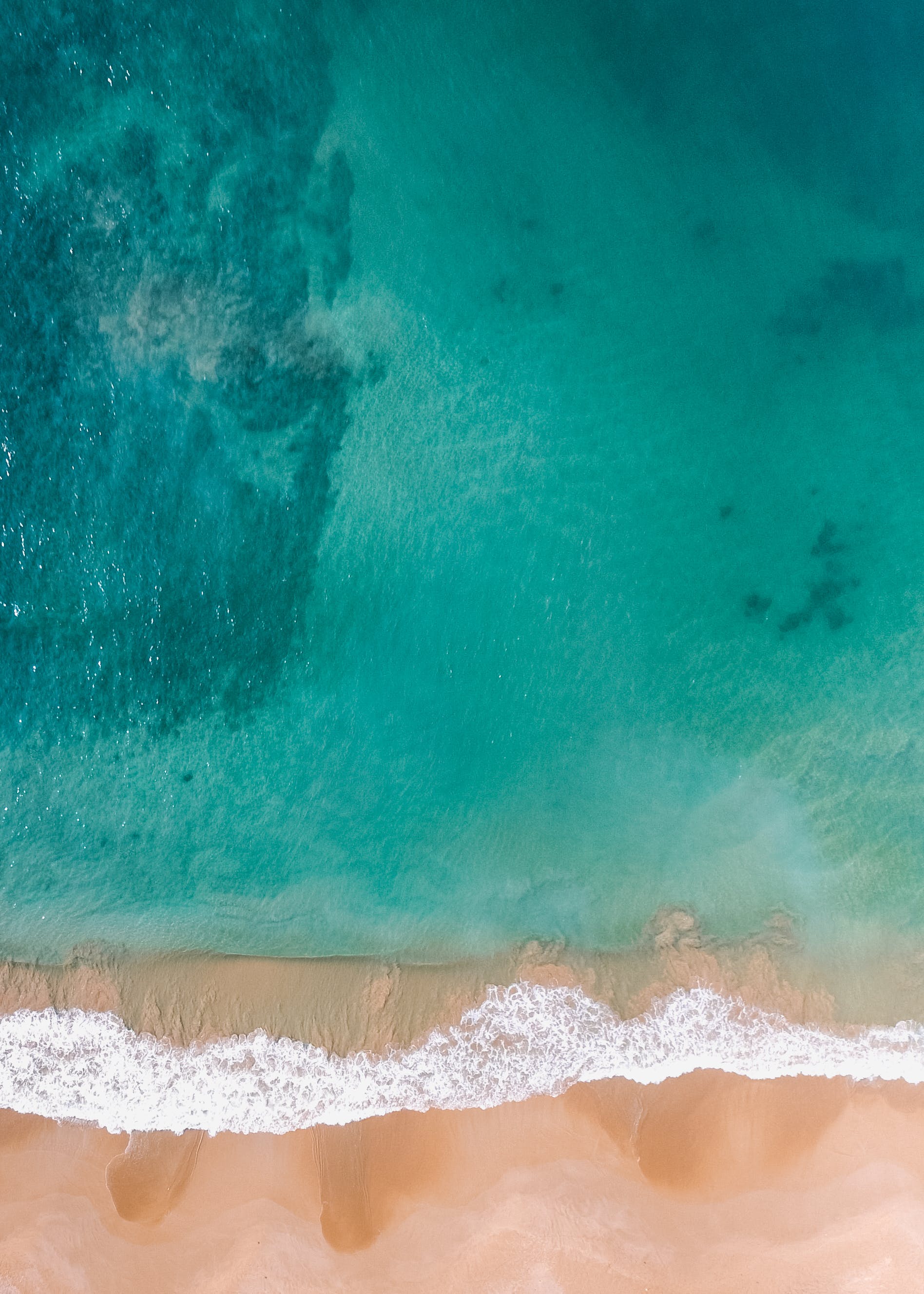 Aerial drone shot — turquoise sea meeting golden beach